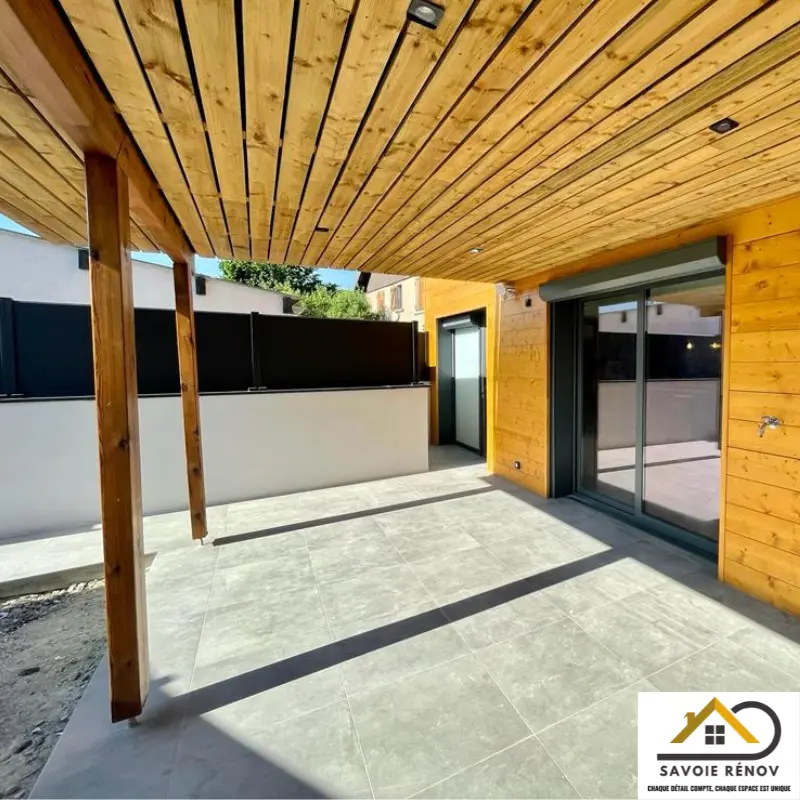 Aménagement extérieur avec terrasse en carrelage et plafond habillé de lames de terrasse en bois.